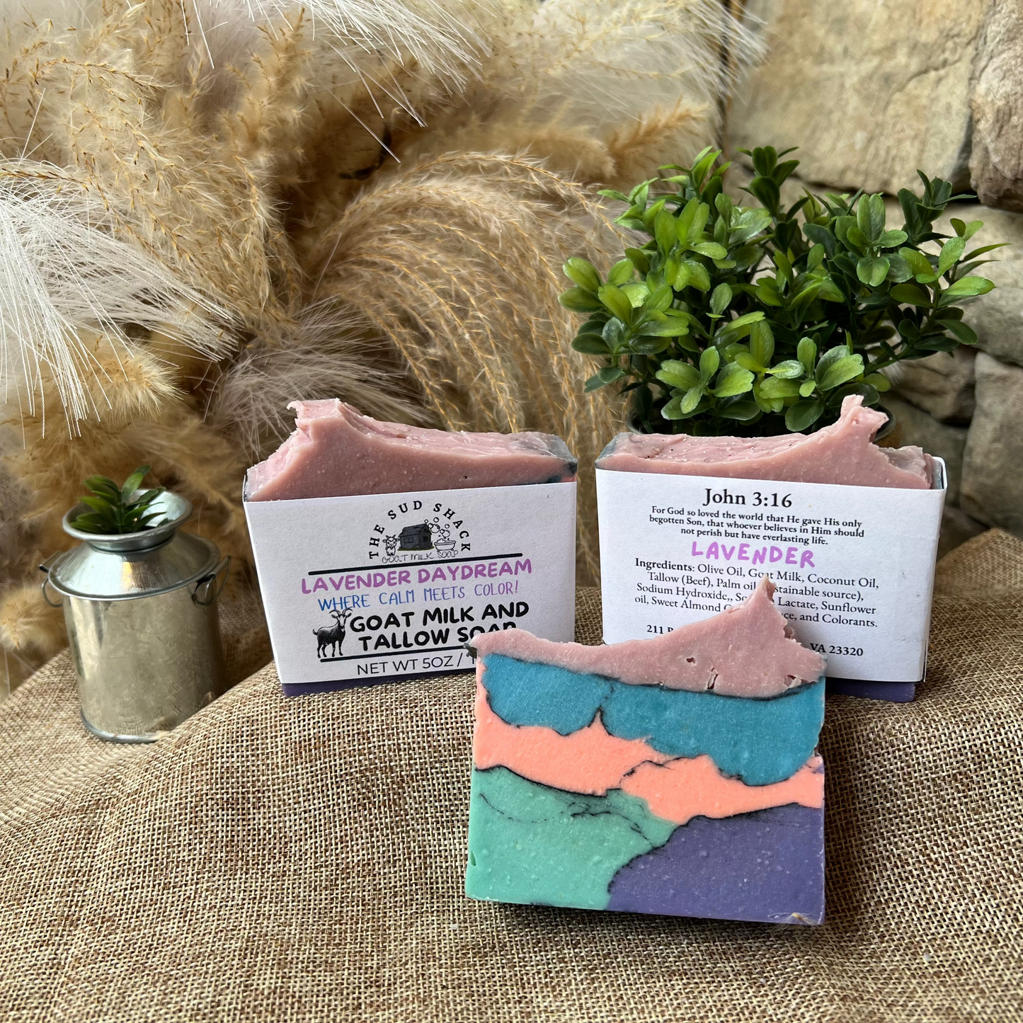 Three bars of soap with colorful designs on a textured surface, with decorative elements in the background.