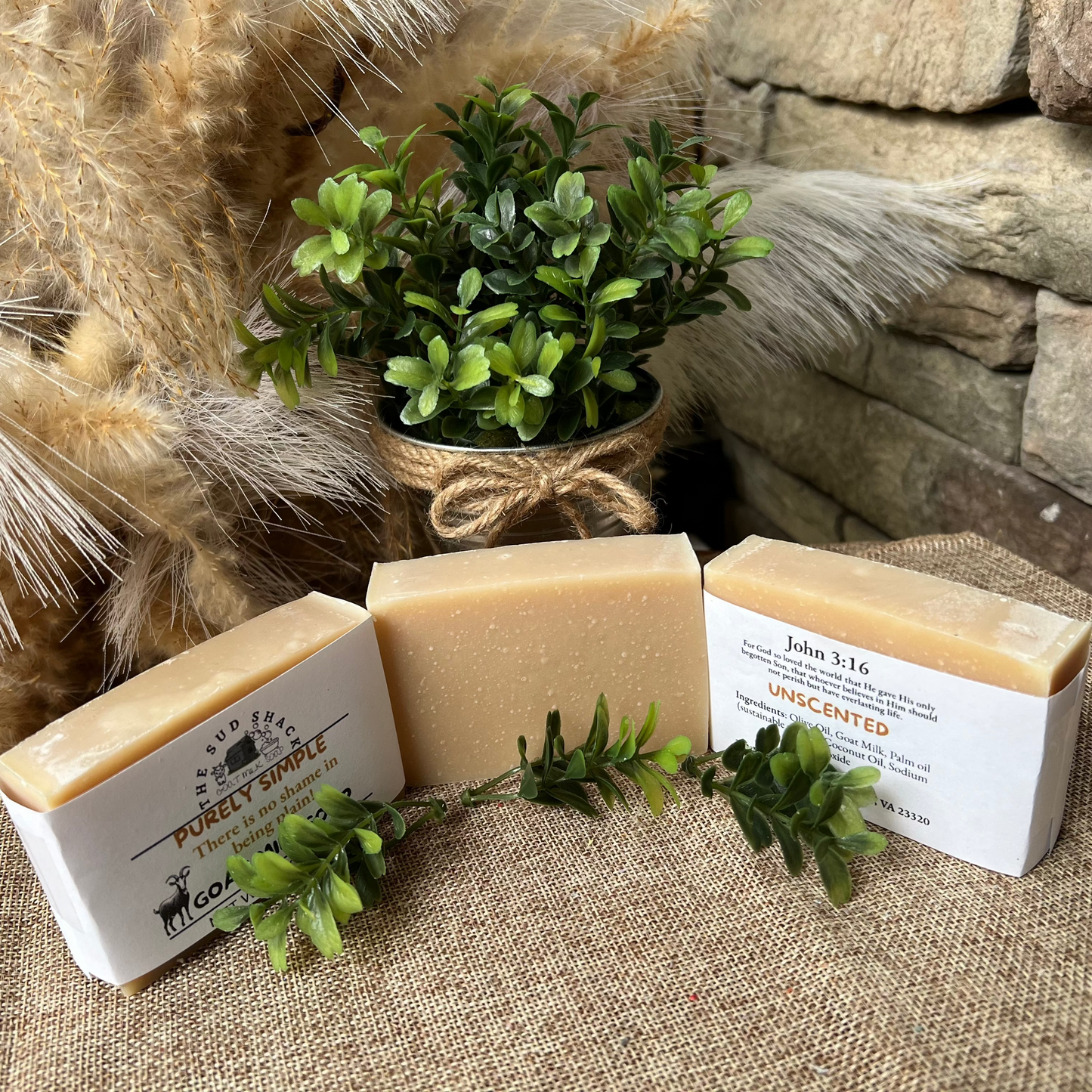 Three bars of soap with labels on a textured surface with decorative elements.