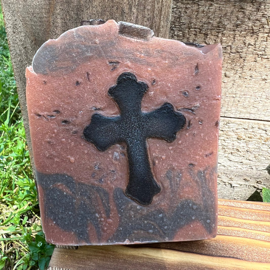 Bar of soap with a black cross design on a wooden surface