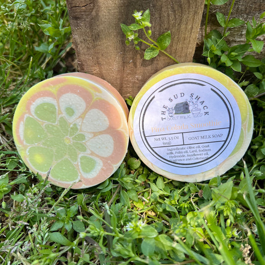 Two goat milk soaps from The Sud Shack on a grassy background