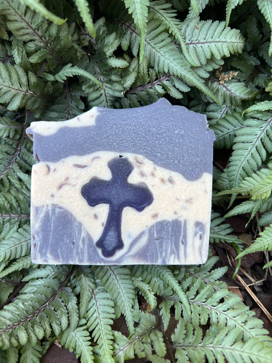 Bar of soap with a cross design on a bed of green ferns