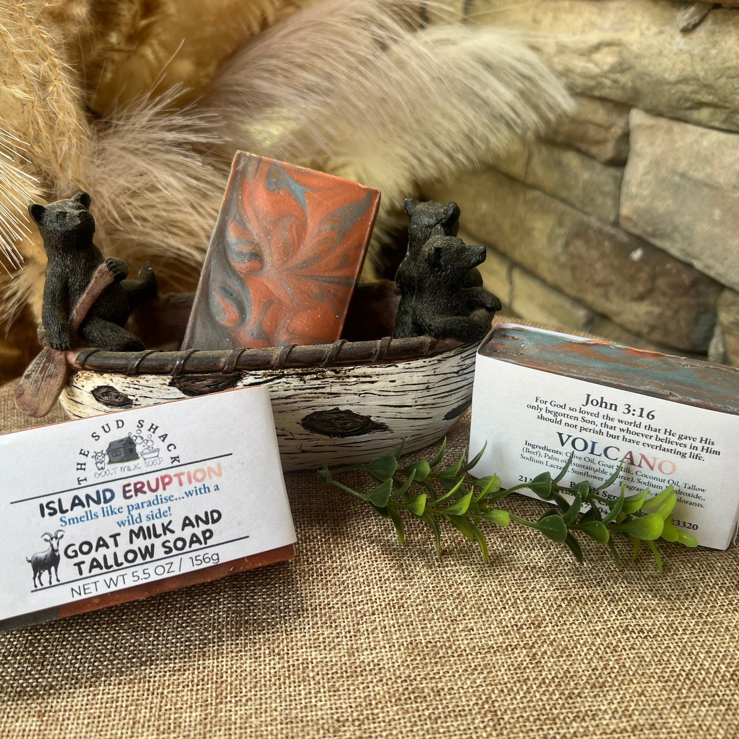 Three bars of soap with packaging on a textured surface with decorative elements with Volcano scent.