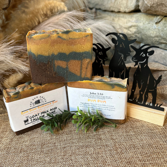 Goat milk and tallow soap with packaging on a textured surface, featuring a decorative goat figure.
