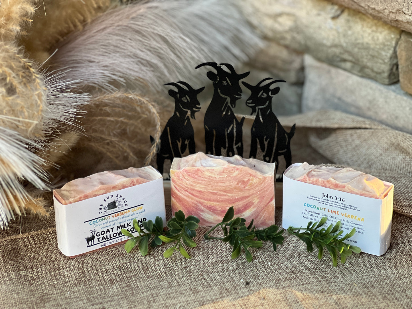 Three bars of soap with visible branding on a textured surface with decorative elements.