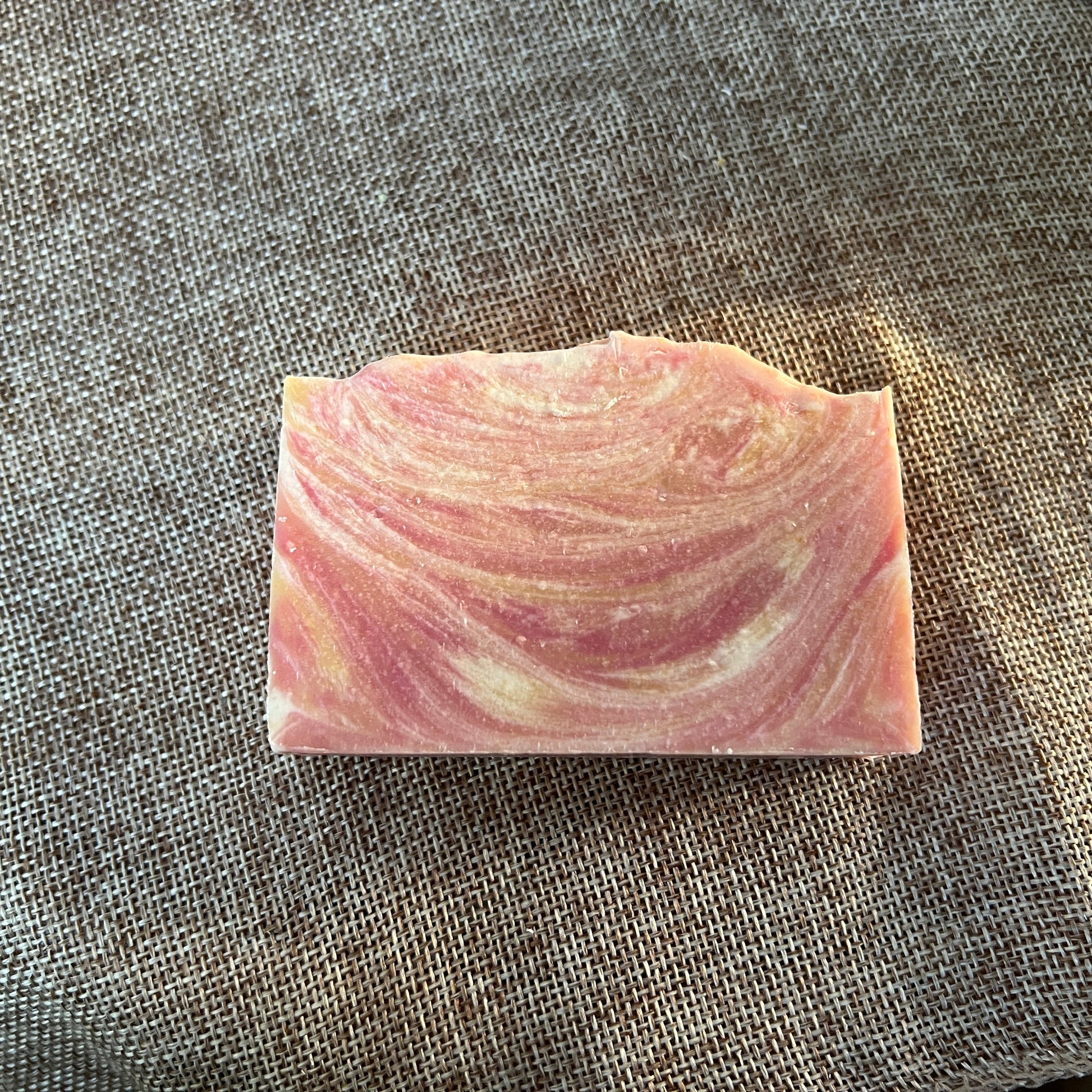 Pink and white swirled soap bar on a textured surface