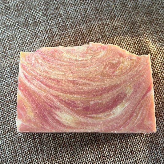 Pink and white swirled soap bar on a textured surface