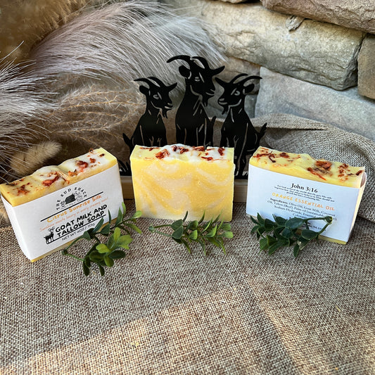 Three bars of soap with labels on a textured surface, surrounded by decorative elements.