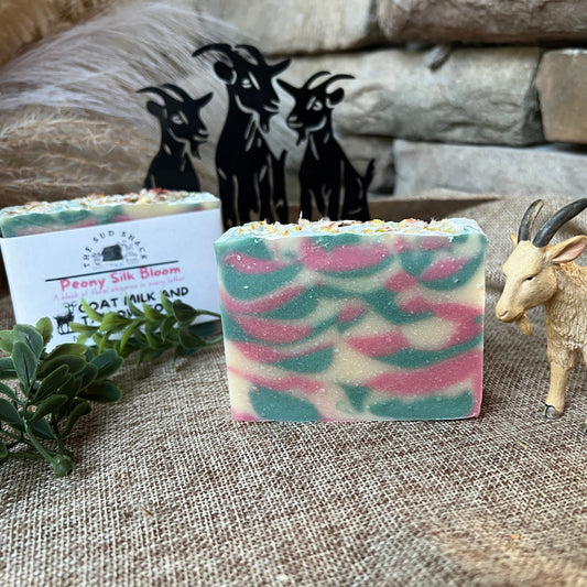 Bar of soap with goat milk and plant extract, surrounded by decorative elements on a textured surface.