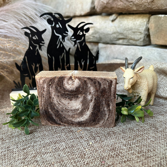 Marble-patterned soap bar with decorative goat figures on a textured surface
