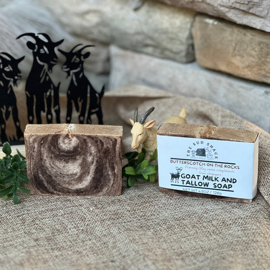 Goat milk and tallow soap with packaging on a textured surface with decorative elements.