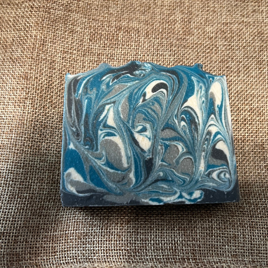 Marbled blue and gray soap bar on a textured brown fabric background