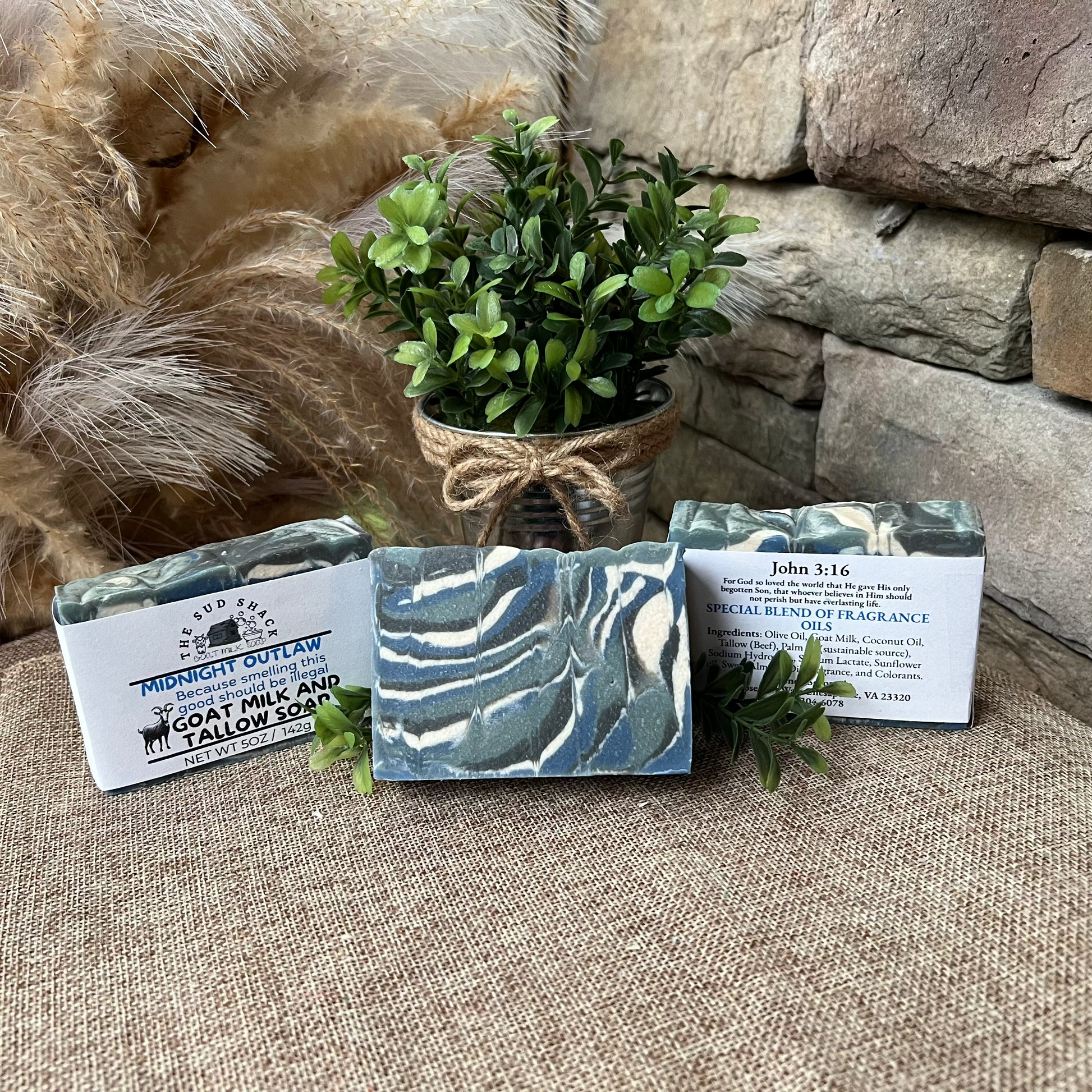 Three soap bars with packaging on a stone surface with decorative elements.