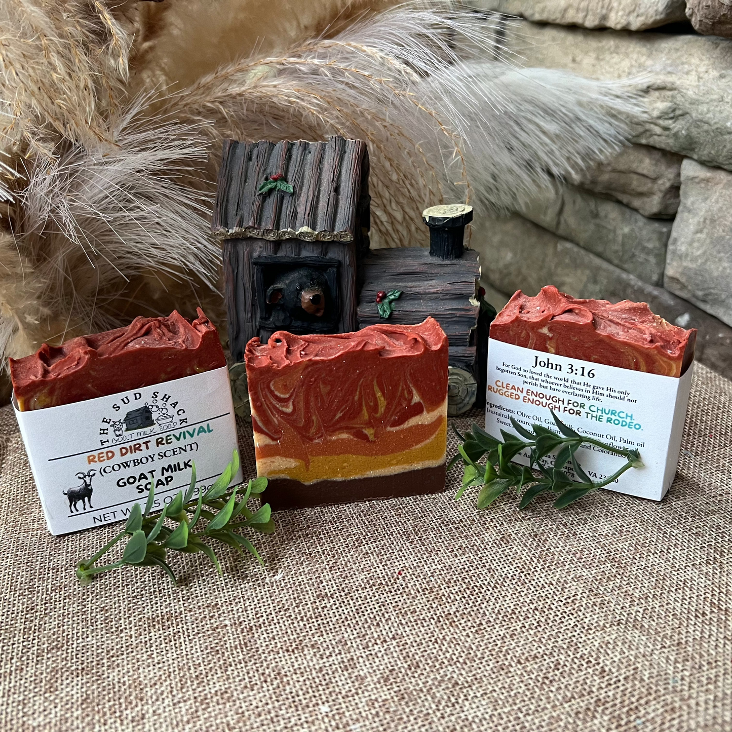 Three soap bars with rustic packaging on a textured surface