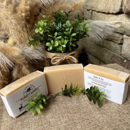 Three bars of soap with labels on a textured surface with decorative elements.