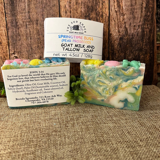 Three bars of soap with decorative packaging on a wooden surface and textured fabric background.