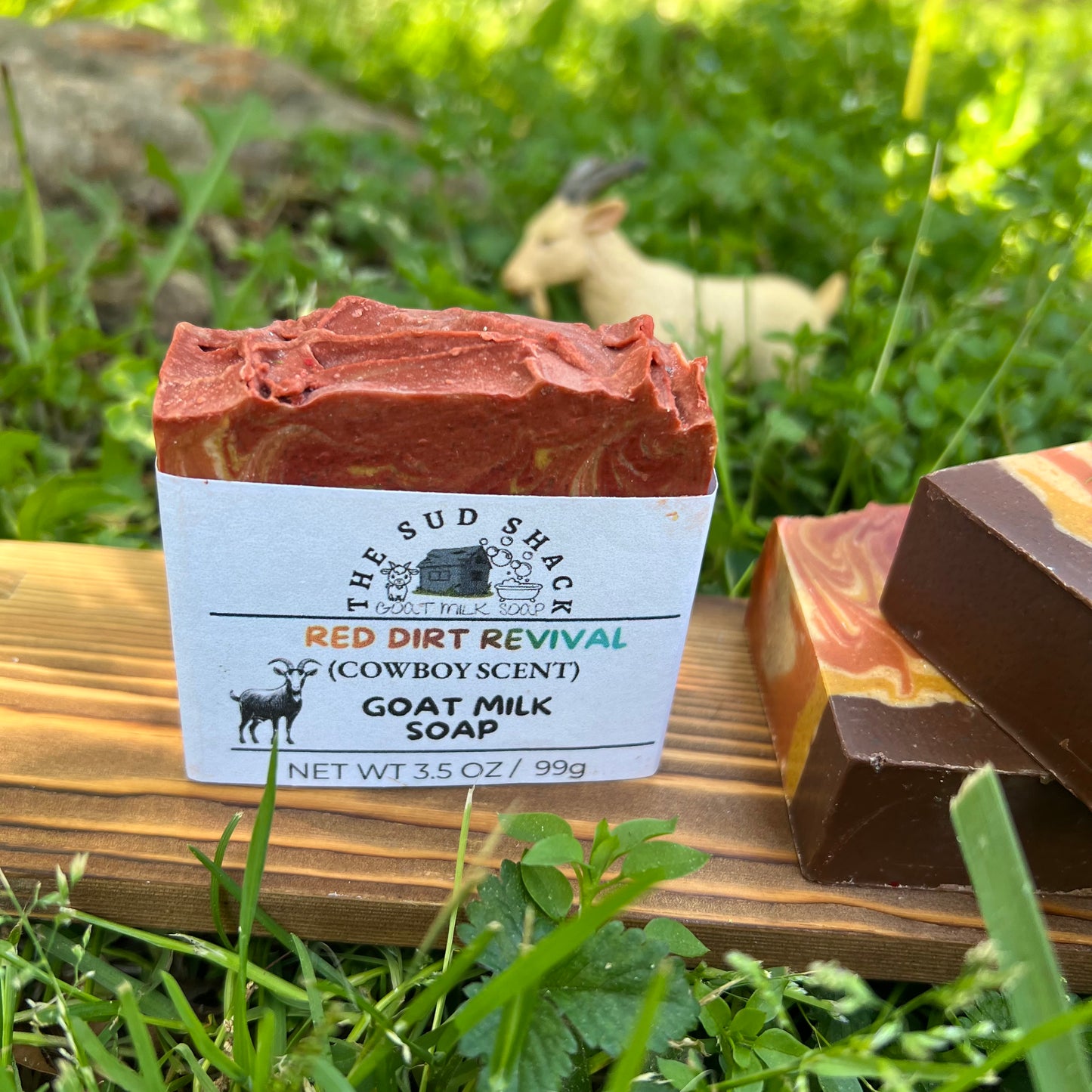 Bar of goat milk soap with a label on a wooden block outdoors