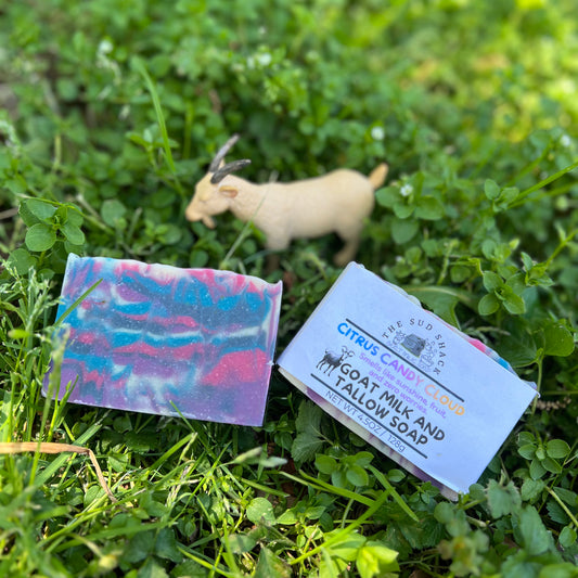 Bar of soap with a label on grass, with a goat in the background