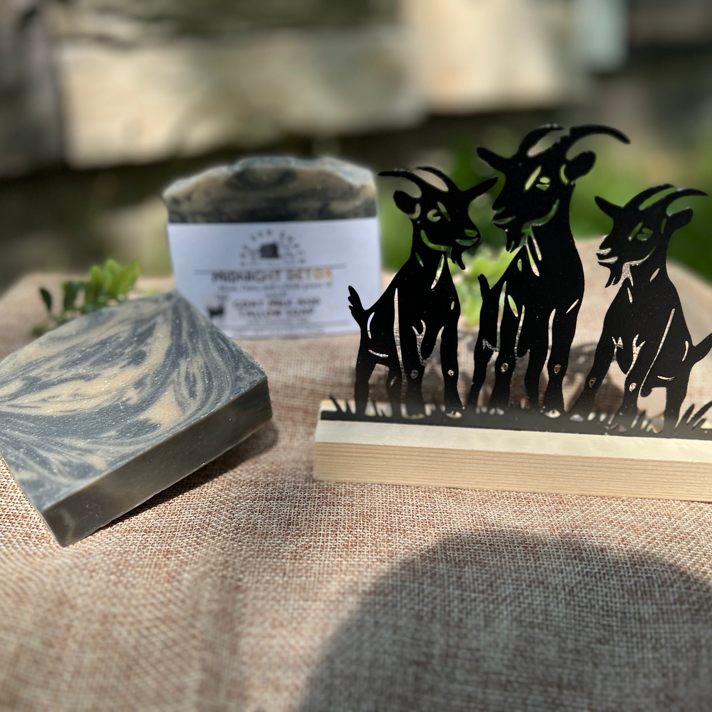 Marble-patterned soap bar with a decorative stand featuring goat silhouettes on a textured surface.