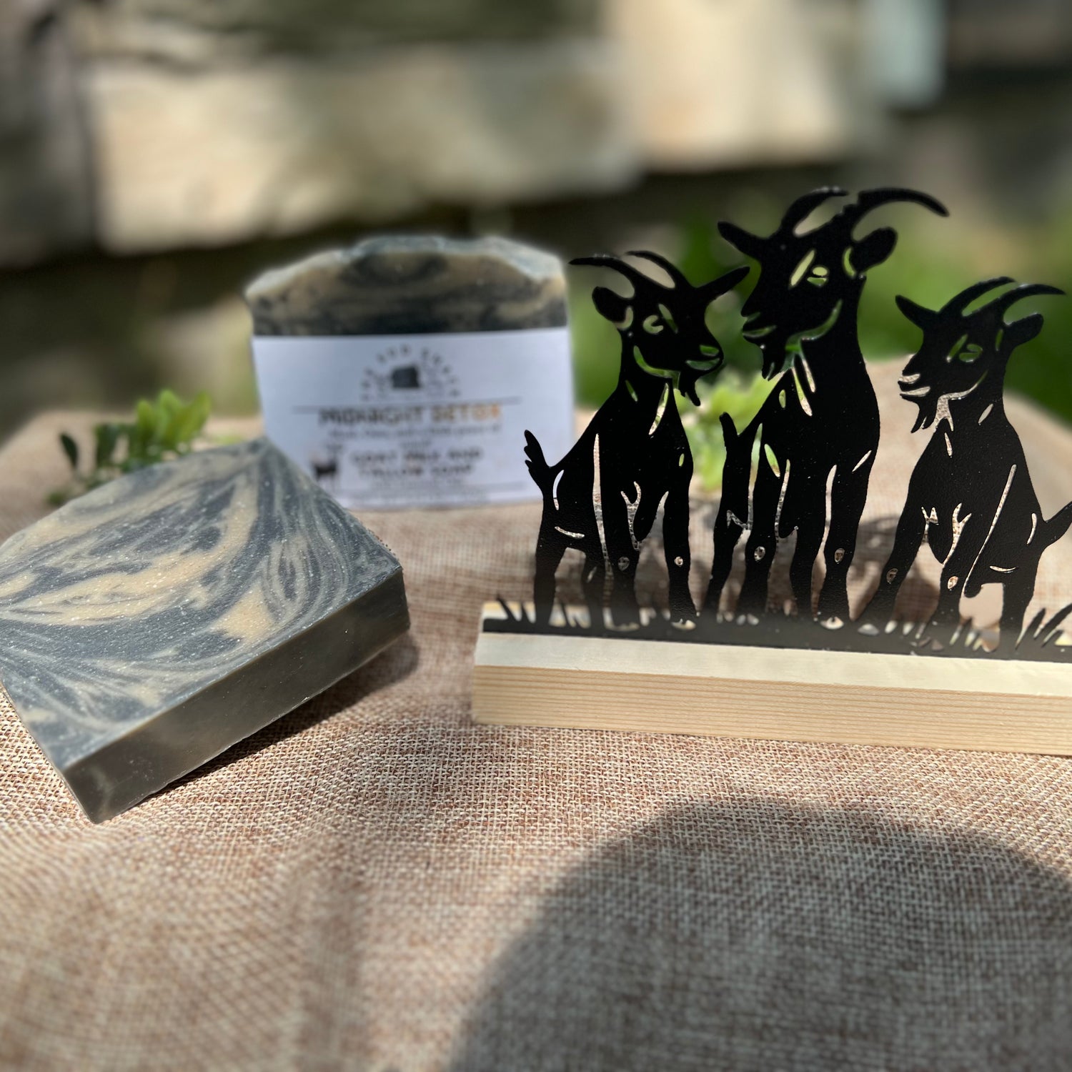 Marble-patterned soap bar with a decorative stand featuring goat silhouettes on a textured surface.