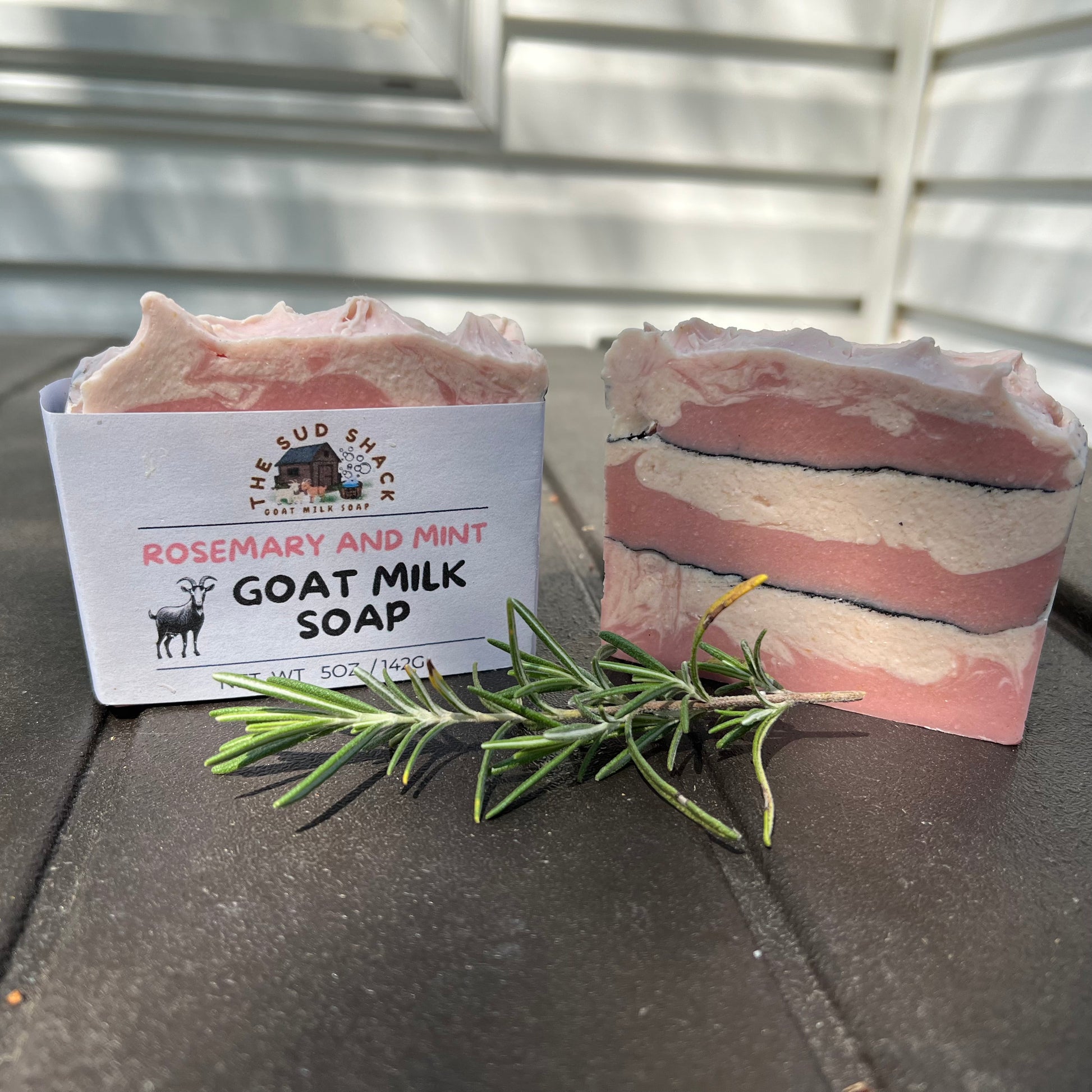 Goat milk soap with rosemary and mint essential oils,  displayed with a label on a dark surface.