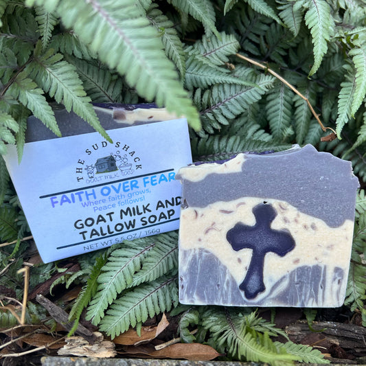 Bar of soap with a cross design on a label, surrounded by green foliage.
