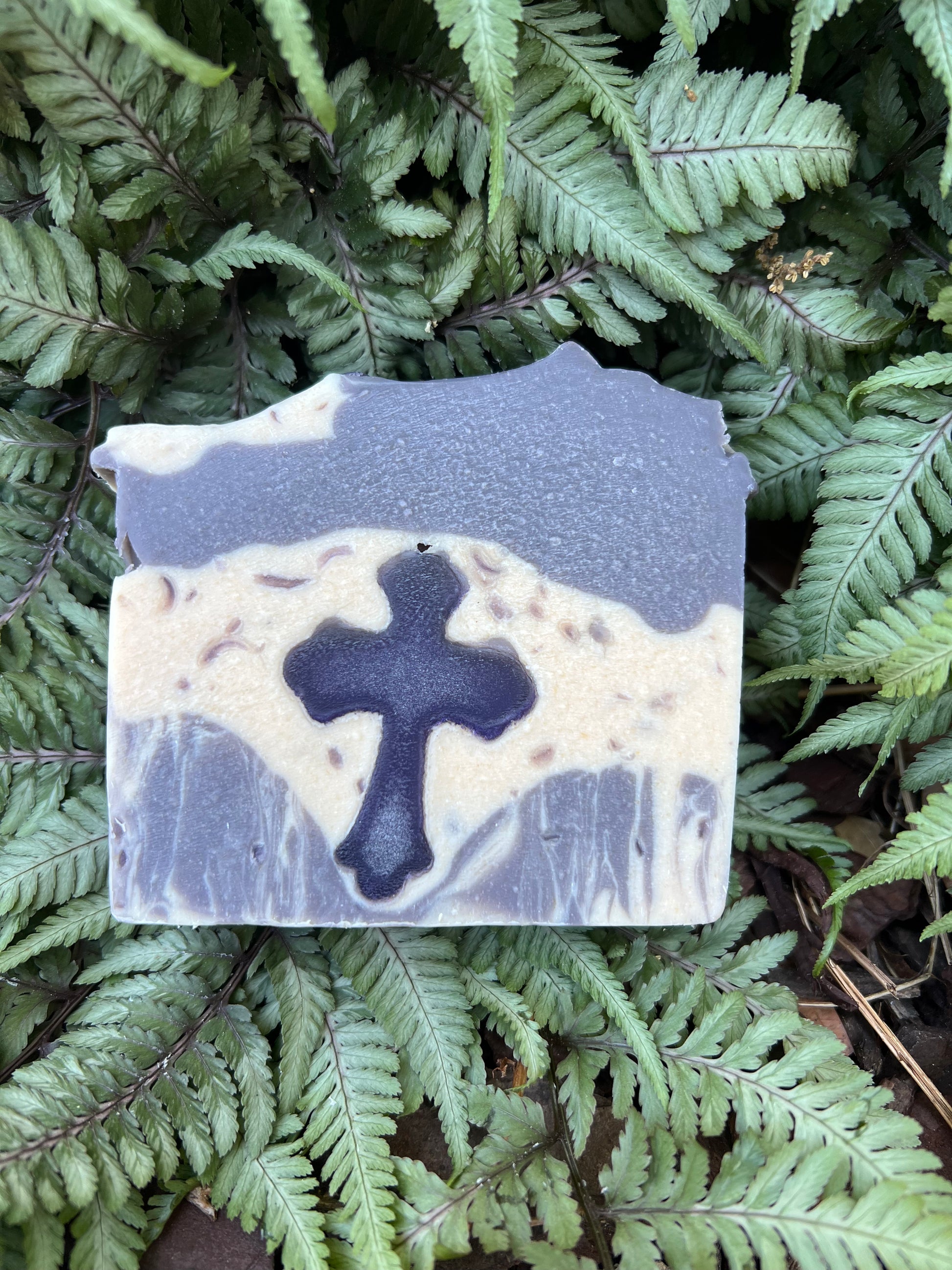 Bar of soap with a cross design on a bed of green ferns