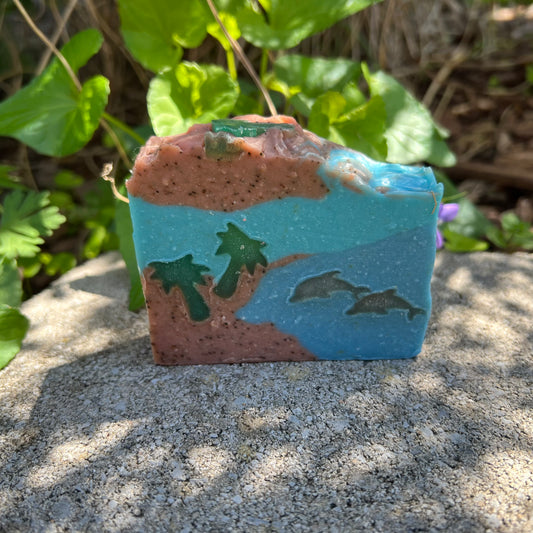 Decorative soap with beach scene design on a stone surface with greenery in the background