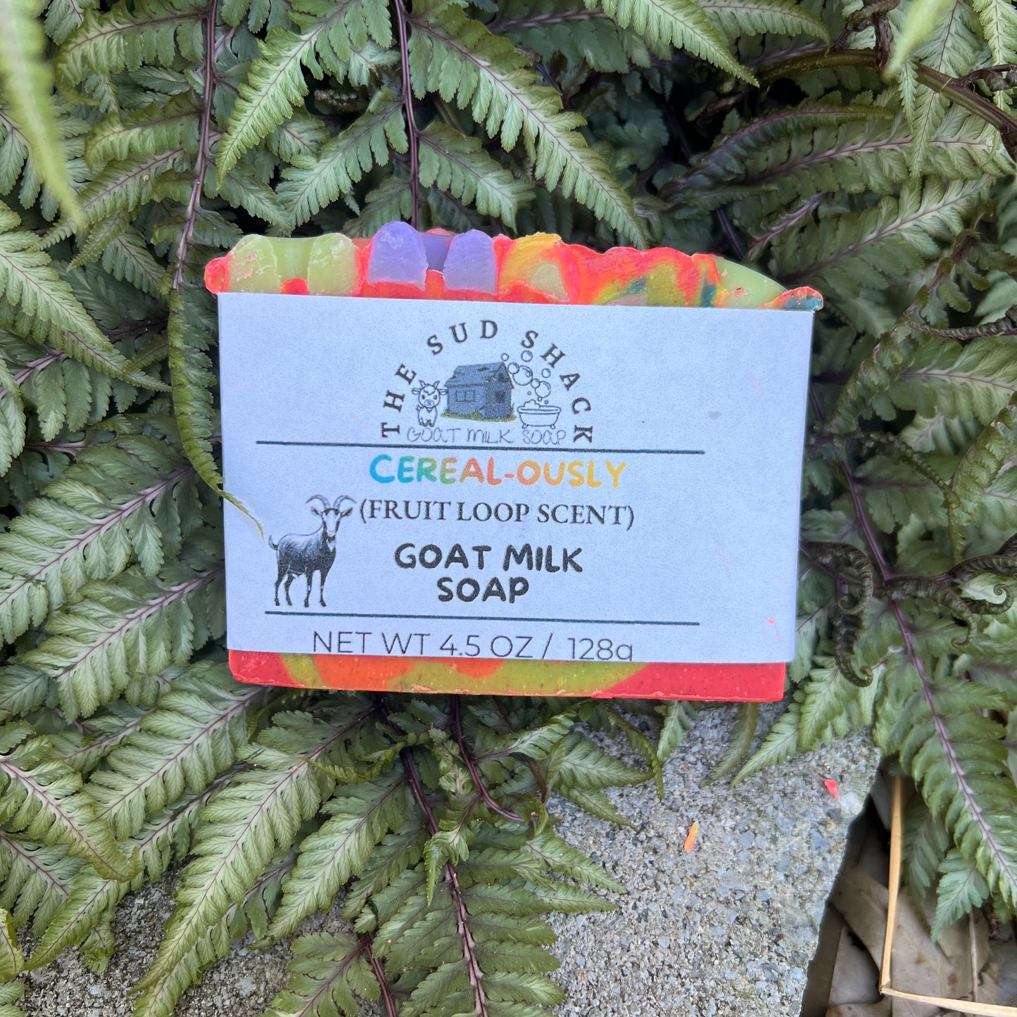 Goat milk soap bar with a label on a bed of ferns