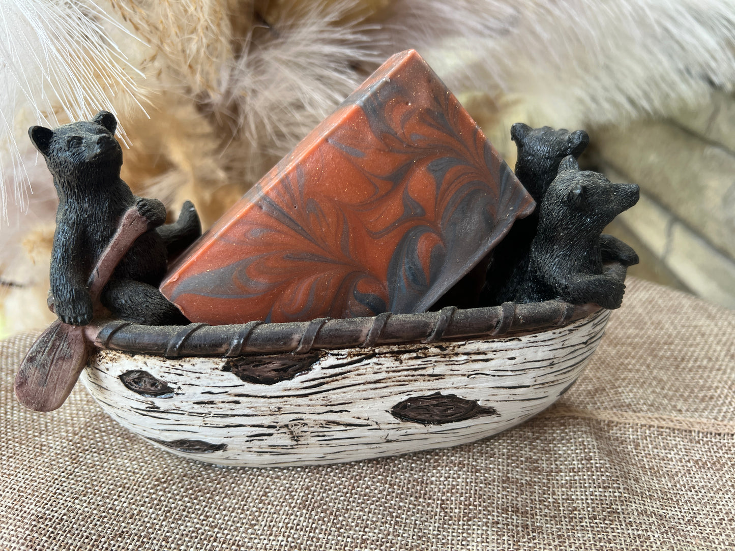 Decorative soap with bear figurines in a boat on a textured surface