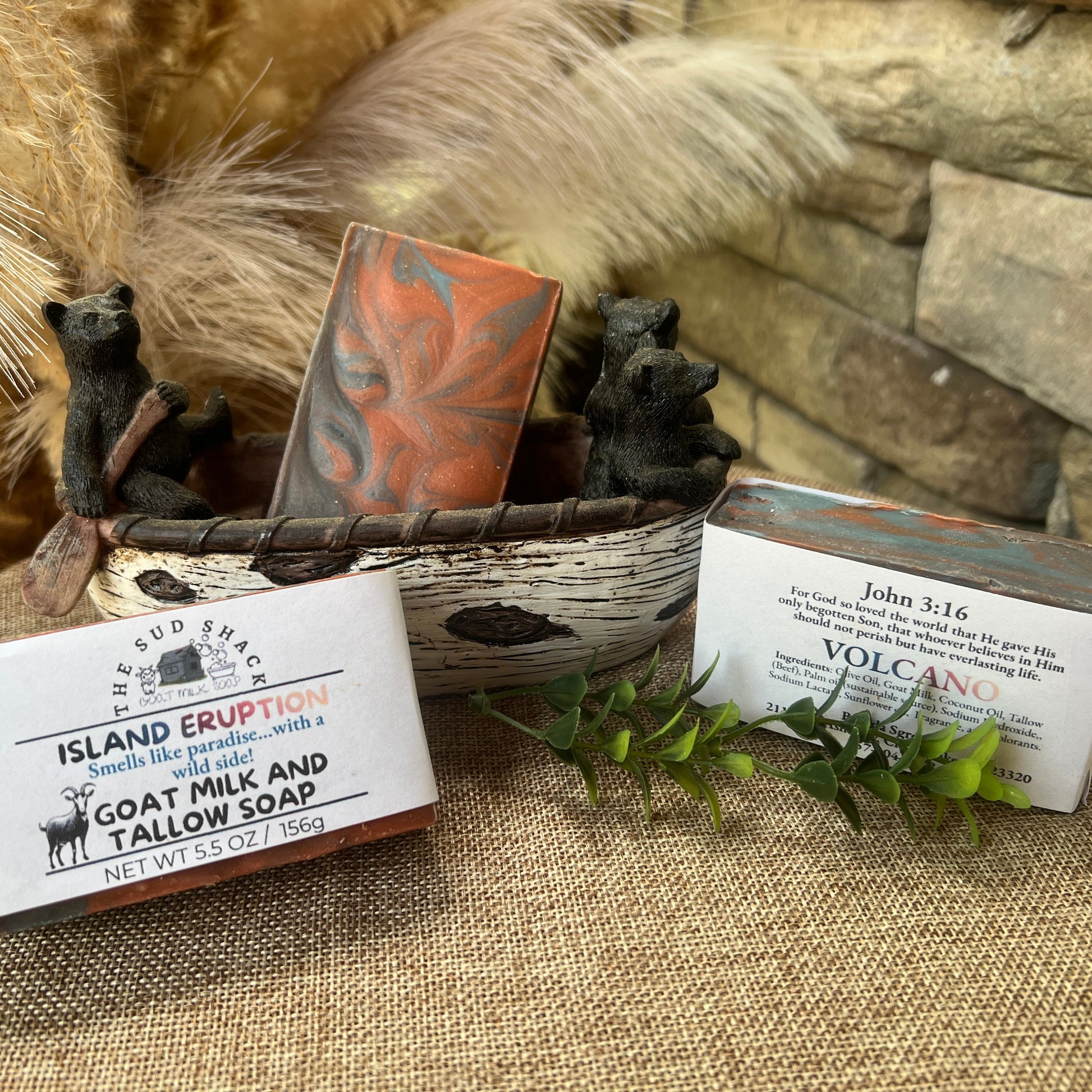 Three bars of soap with packaging on a textured surface with decorative elements with Volcano scent.