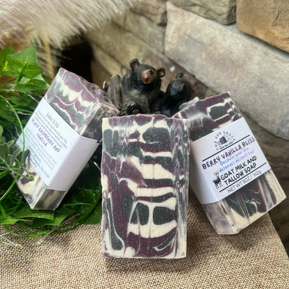 Three soap bars with packaging on a stone surface with greenery