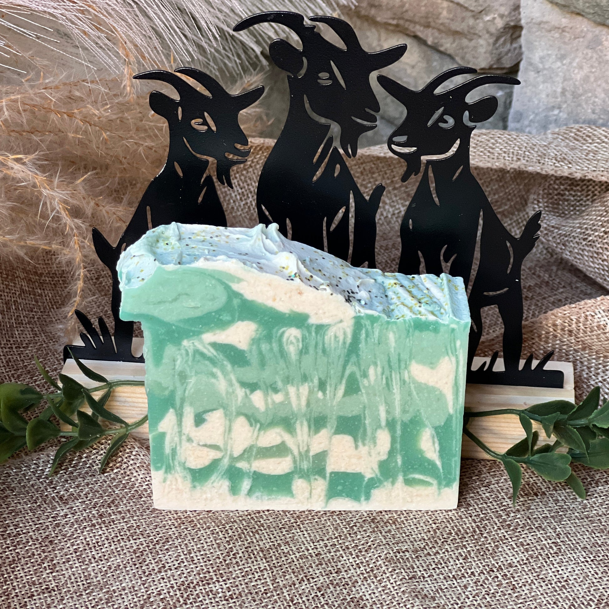 Green and white soap bar with black goat figurines in the background