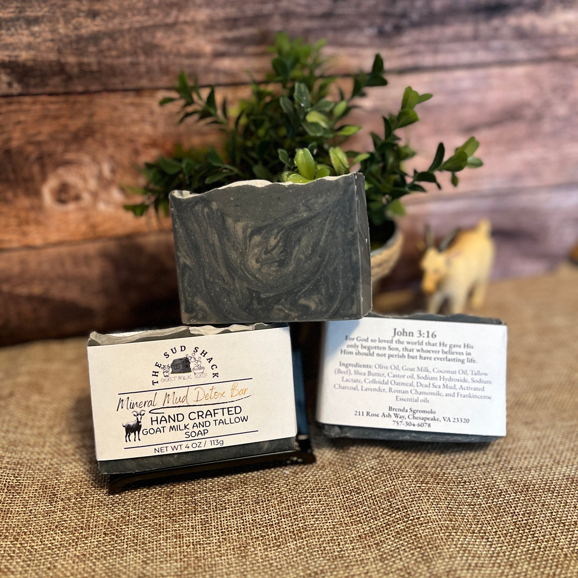 Three bars of soap with labels on a textured surface with a wooden background