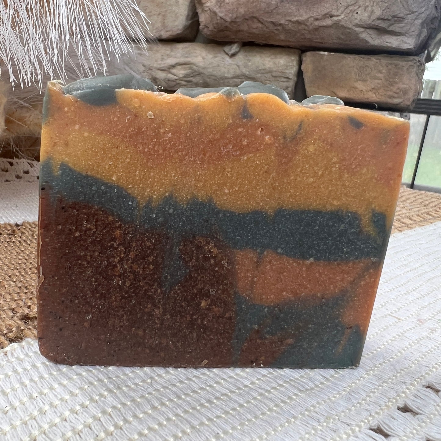 Multicolored soap on a textured surface with stone and plant decor in the background