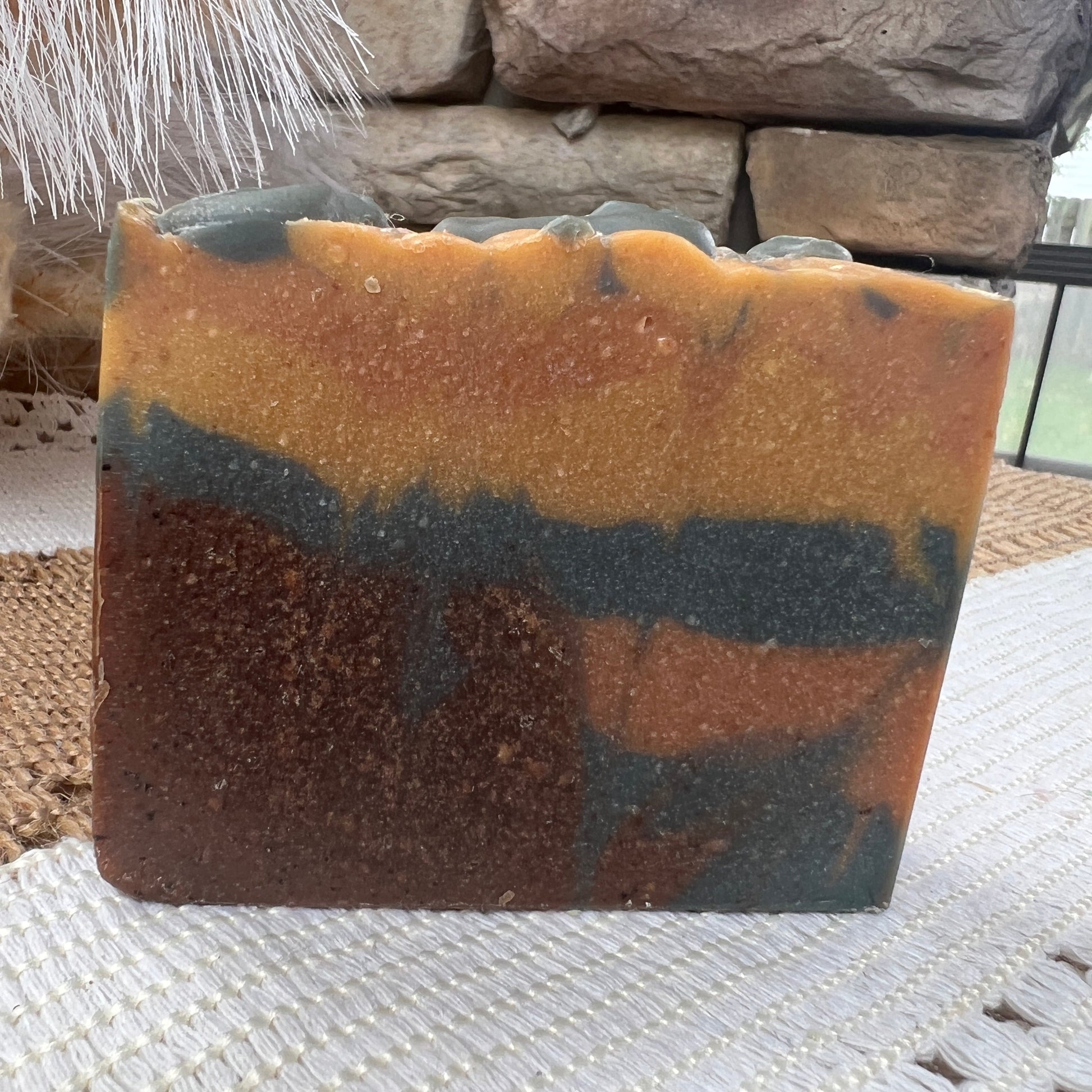 Multicolored soap on a textured surface with stone and plant decor in the background