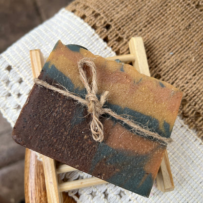 Handmade soap bar with rustic design on a small wooden stand.